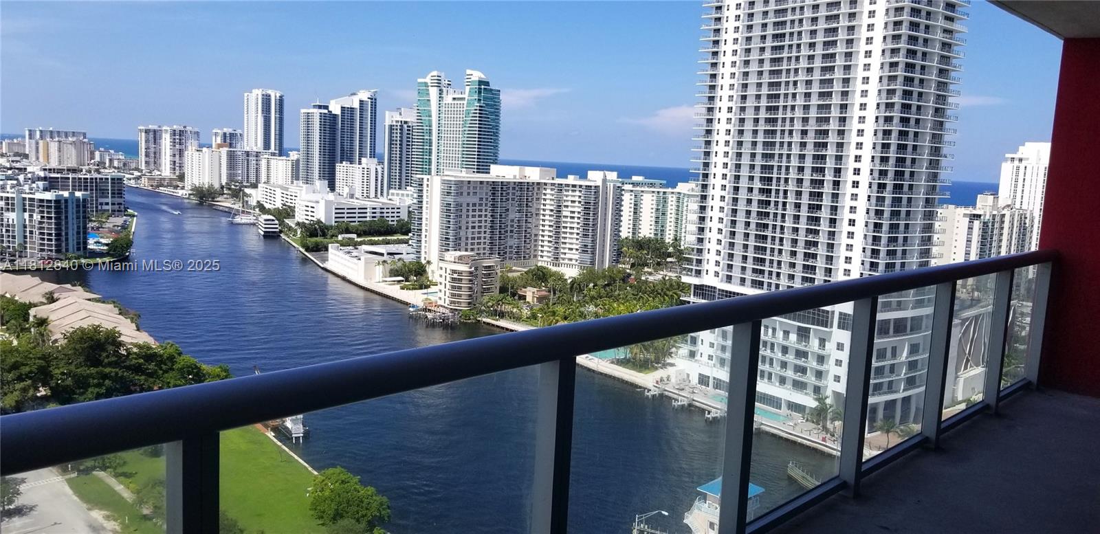 A high-angle view from a balcony overlooking a canal, surrounding high-rise buildings, and the ocean — 2602 E Hallandale Beach Blvd # R2010, Hallandale Beach FL 33009, HALLANDALE BEACH, FL