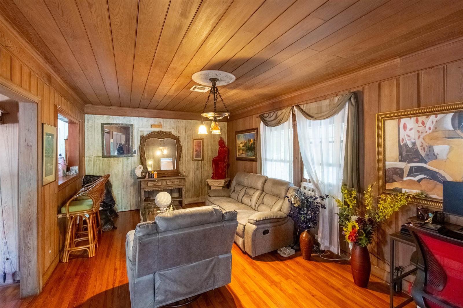 A living room features wood-paneled walls and ceilings, a gray sofa, and a matching recliner — 1016 N E Street, FL 33460, FL