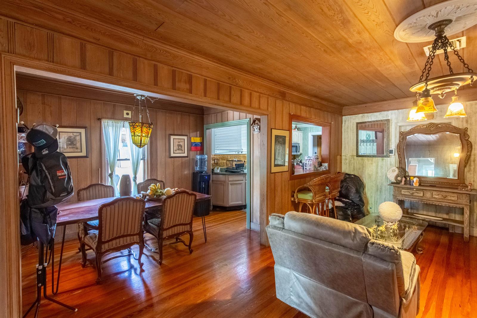 A living and dining area features wood-paneled walls, hardwood floors, and a decorative ceiling fixture — 1016 N E Street, FL 33460, FL