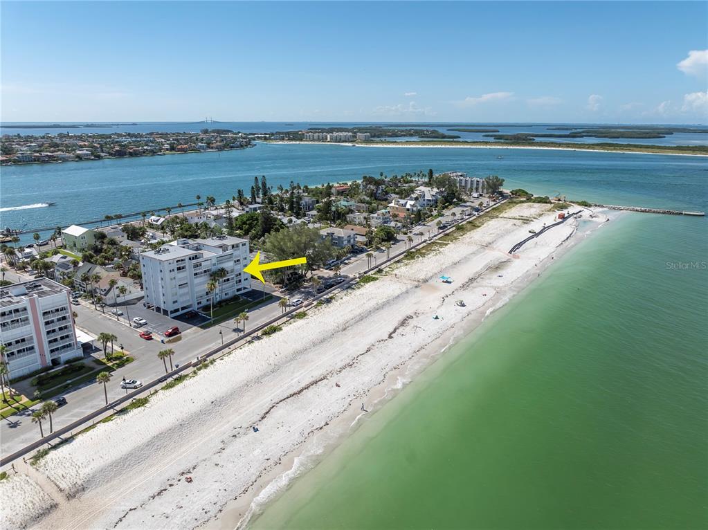 An aerial view shows a multi-story apartment building located directly across from a sandy beach — 403 GULF WAY UNIT 302, ST PETE BEACH, FL