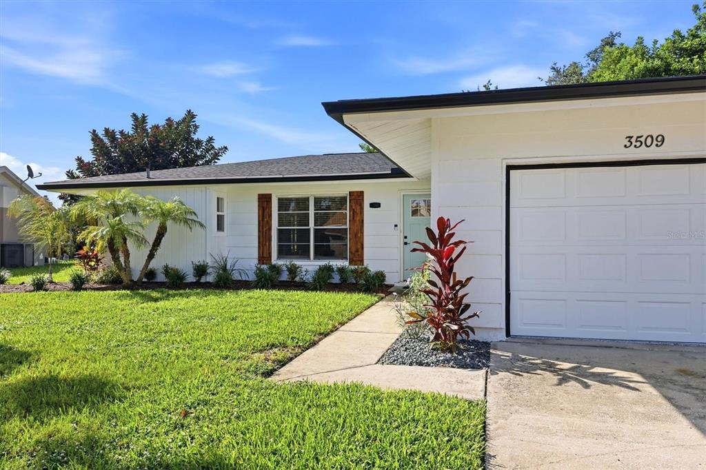 A white single-story house features a garage, a light blue front door, and wood-trimmed windows — 3509 64TH STREET W, BRADENTON, FL