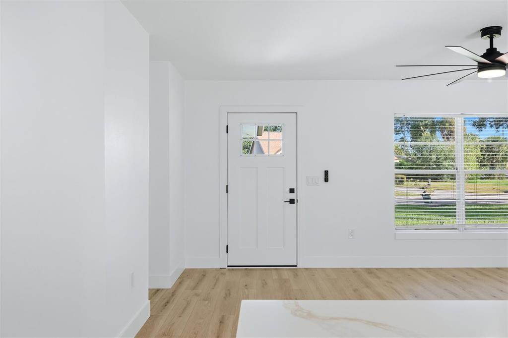 A bright room features white walls, light wood flooring, a white front door, and windows — 3509 64TH STREET W, BRADENTON, FL