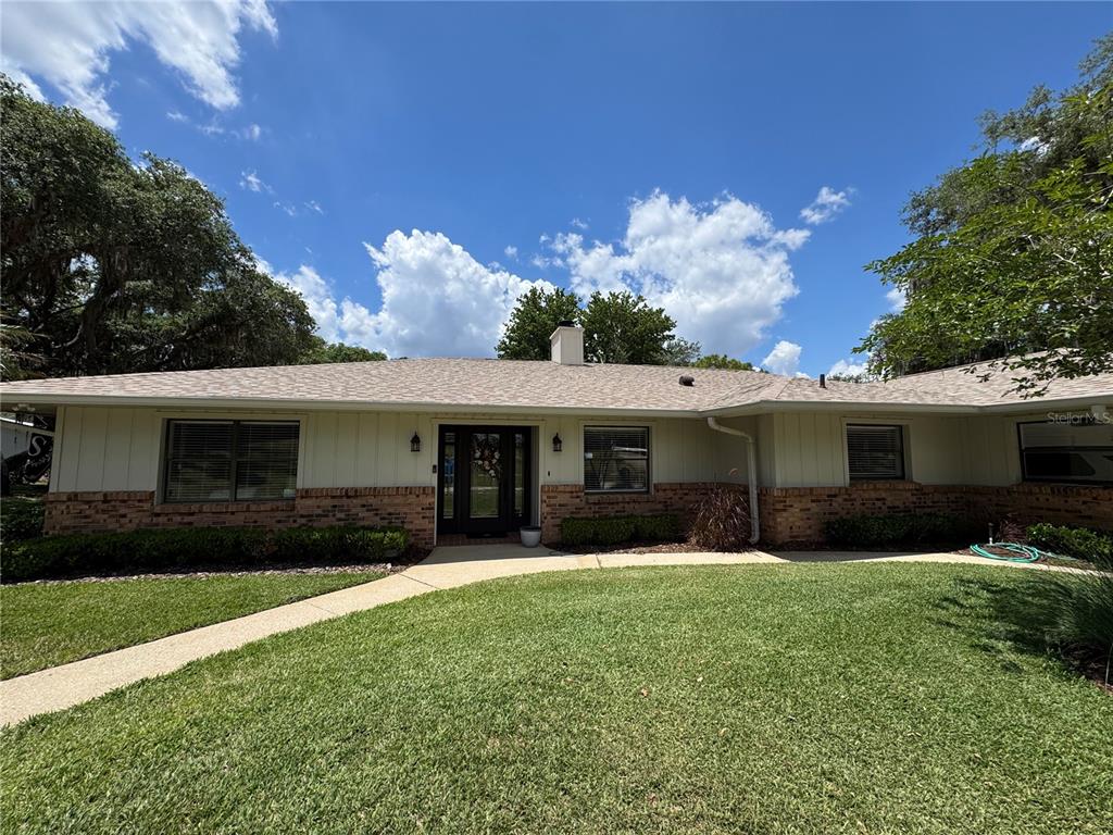 A single-story house with a brick and vertical siding exterior, a shingled roof, and lawn — 334 W F STREET FL, FROSTPROOF, FL