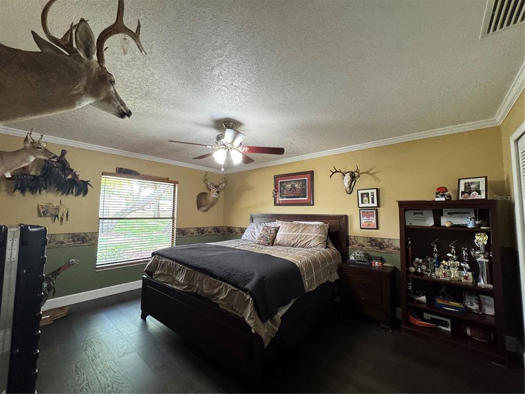 A bedroom features a bed, dark wood furniture, hunting-themed decor, and a ceiling fan — 334 W F STREET FL, FROSTPROOF, FL