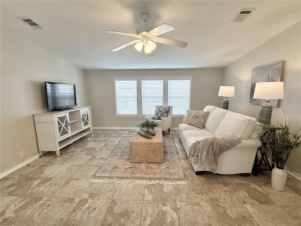 A living room features tile flooring, a white sofa, a coffee table, and a television — 7107 MOUNT ESSEX DRIVE NE UNIT 520, ST PETERSBURG, FL