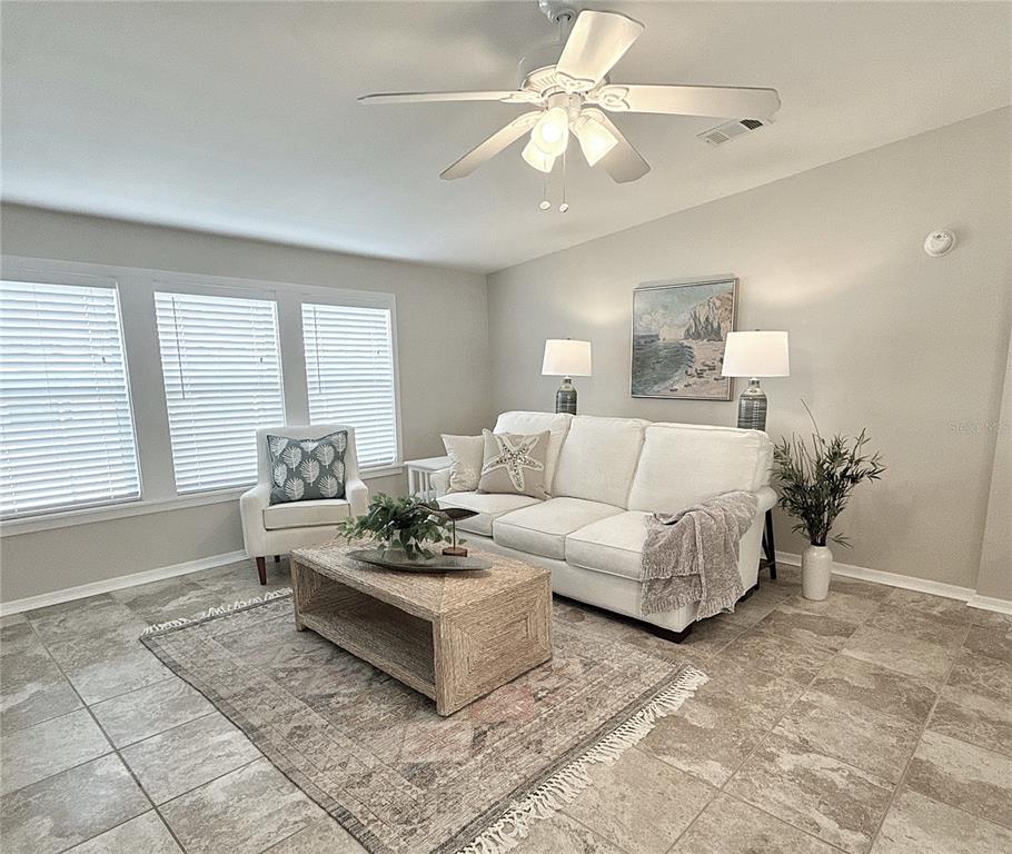 A living room features a white sofa, a wooden coffee table, and tile flooring — 7107 MOUNT ESSEX DRIVE NE UNIT 520, ST PETERSBURG, FL