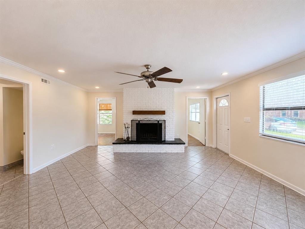 A living room features a white brick fireplace, tile flooring, and a ceiling fan — 7301 N DARTMOUTH AVENUE, TAMPA, FL
