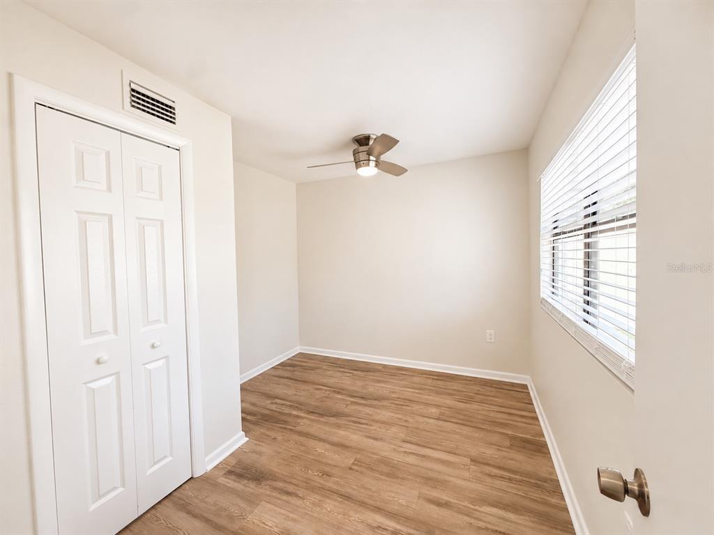 An empty bedroom features light-colored walls, wood-look flooring, a ceiling fan, and a window — 7301 N DARTMOUTH AVENUE, TAMPA, FL