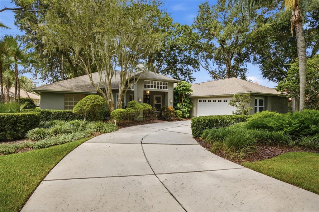 A single-story house with a concrete driveway, a two-car garage, and mature landscaping — 16416 WINDSOR PARK DRIVE, LUTZ, FL