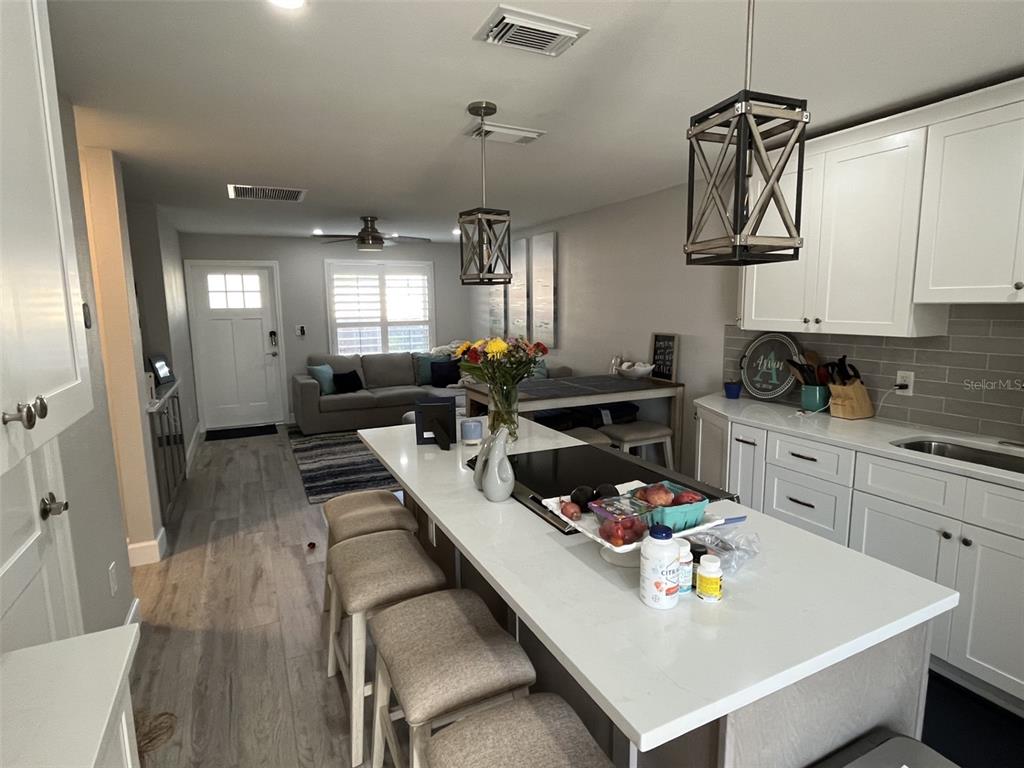 A kitchen with white cabinets and a central island overlooks a living area with seating — 2369 19TH AVENUE SW UNIT B, LARGO, FL