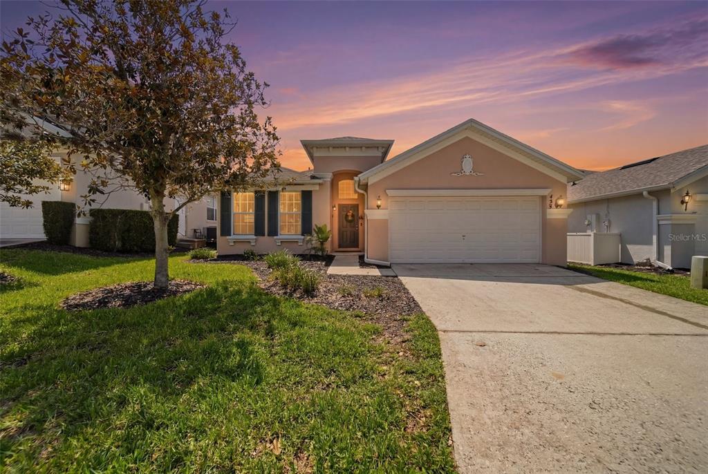 A single-story house with a beige stucco exterior, a two-car garage, and a front lawn — 429 ORISTA DRIVE, DAVENPORT, FL