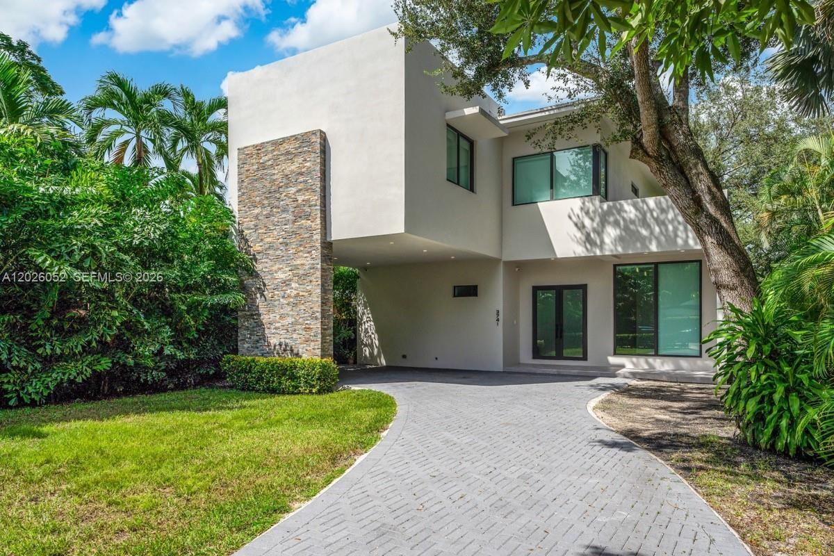 A modern two-story house features a stone-clad pillar, a covered driveway, and lush landscaping — 3741 Kumquat Ave, Miami FL 33133, MIAMI, FL