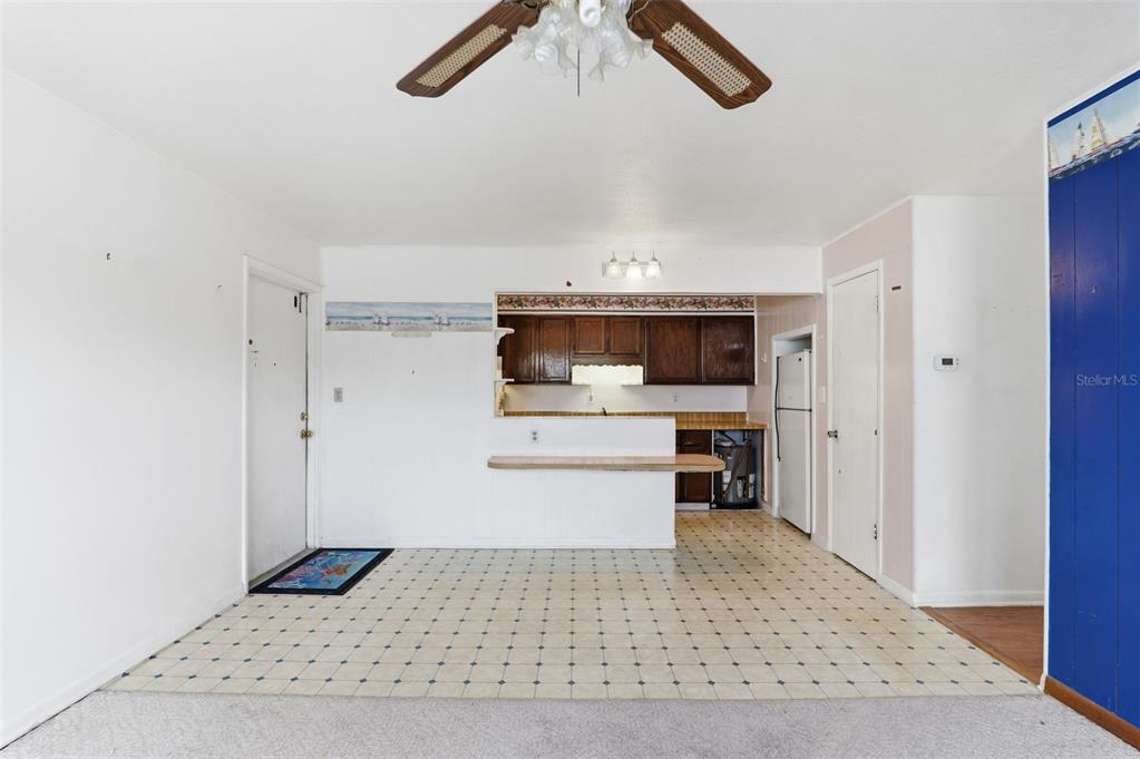 A kitchen with dark wood cabinets and a breakfast bar overlooks a tiled dining area — 302 LINCOLN AVENUE UNIT 12, CAPE CANAVERAL, FL