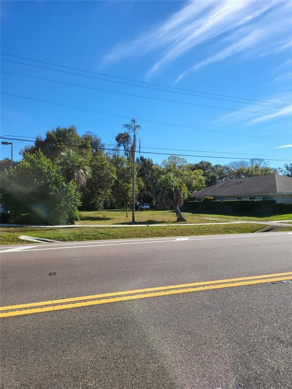 A vacant, grassy lot with palm trees sits next to a house along a road — 2131 COACHMAN ROAD NE, CLEARWATER, FL