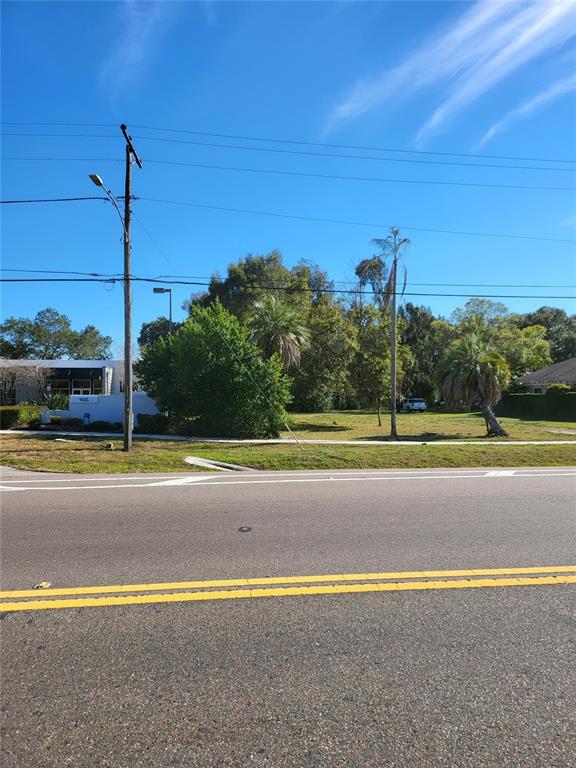 A vacant grassy lot sits next to a commercial building under a clear blue sky — 2131 COACHMAN ROAD NE, CLEARWATER, FL