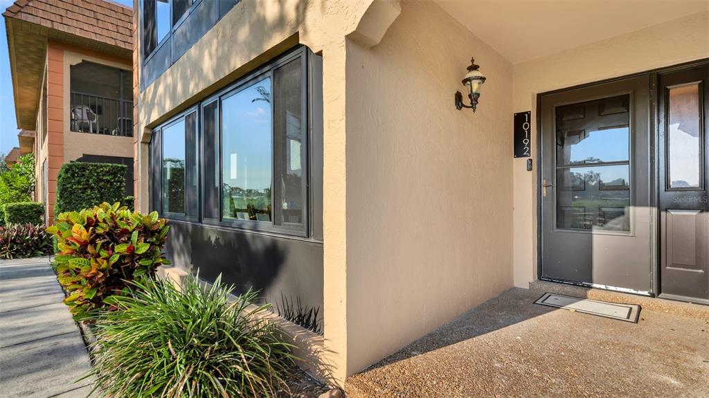 The exterior of a tan building features a dark-framed window and a dark front door — 10192 SEMINOLE ISLAND DRIVE UNIT 10192, LARGO, FL