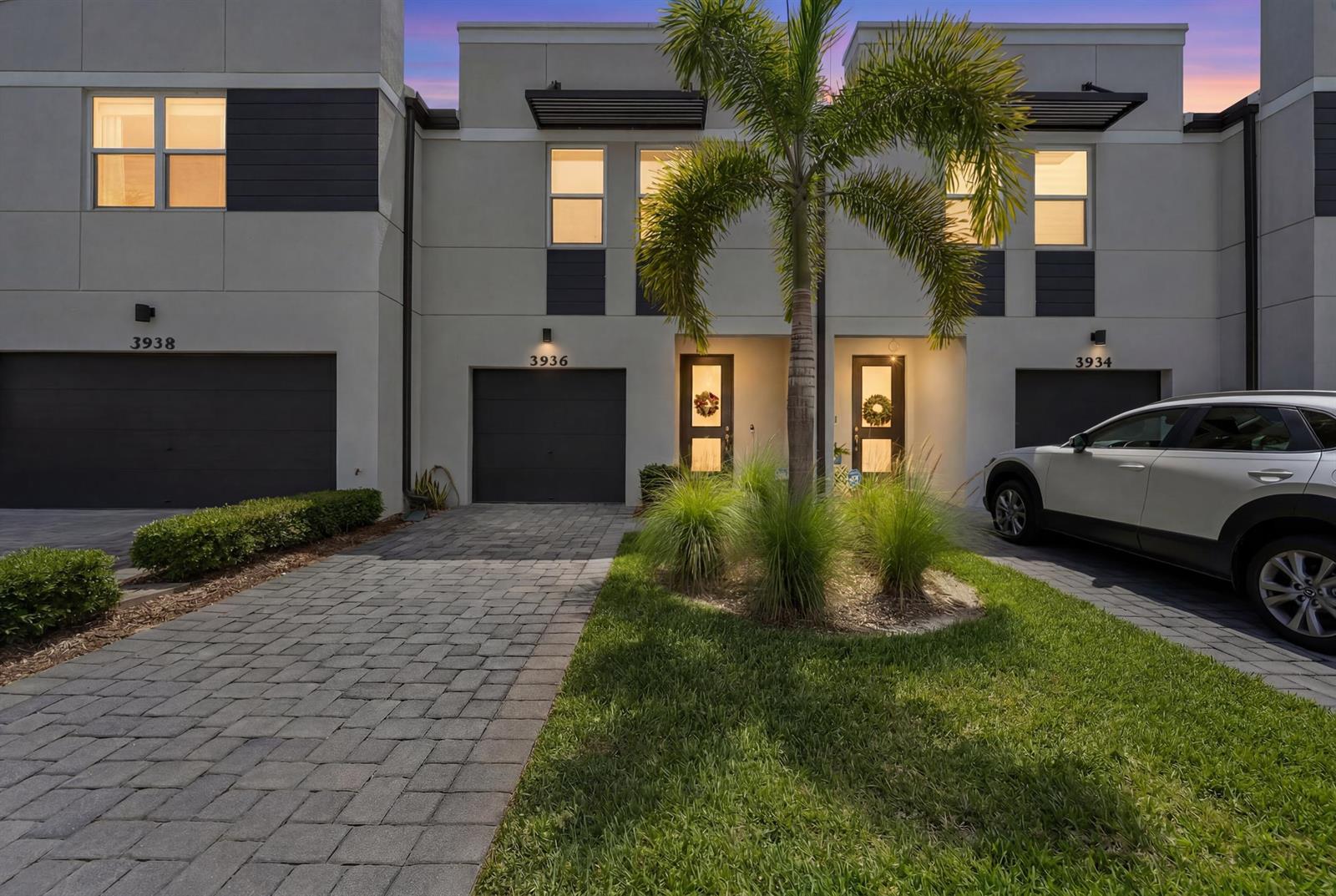 A row of modern townhomes features paved driveways, attached garages, and a central palm tree — 3936 SE Caladium Court # 3936, Stuart FL 34997, STUART, FL