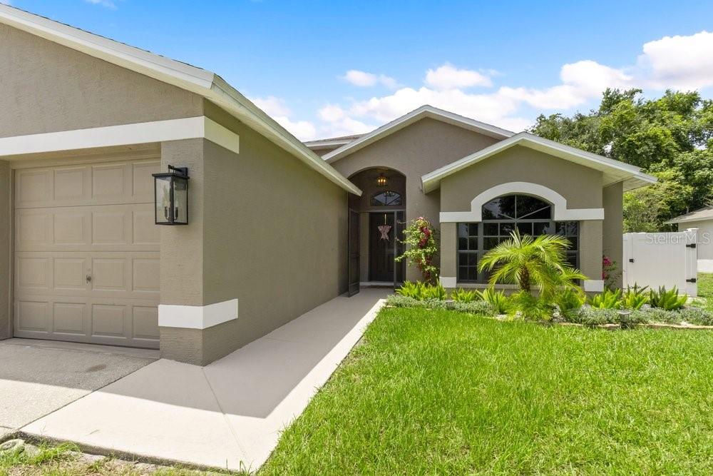 A single-story house with a tan stucco exterior, a one-car garage, and a front walkway — 10551 MAGRATH LANE, NEW PORT RICHEY, FL