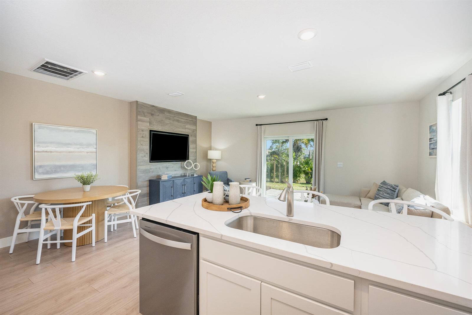 A kitchen island with a sink overlooks an open-concept living and dining area — 8128 Cobblestone Drive, Fort Pierce FL 34945, FORT PIERCE, FL