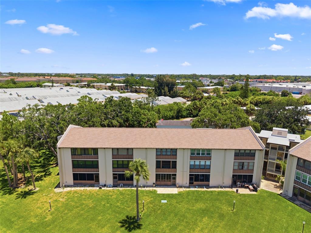 An aerial view shows a three-story apartment building with a brown roof and green lawn — 5245 AMULET DRIVE UNIT 306, NEW PORT RICHEY, FL