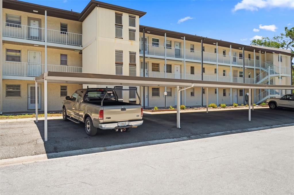 A three-story apartment building with exterior walkways and a covered parking area in front — 5245 AMULET DRIVE UNIT 306, NEW PORT RICHEY, FL