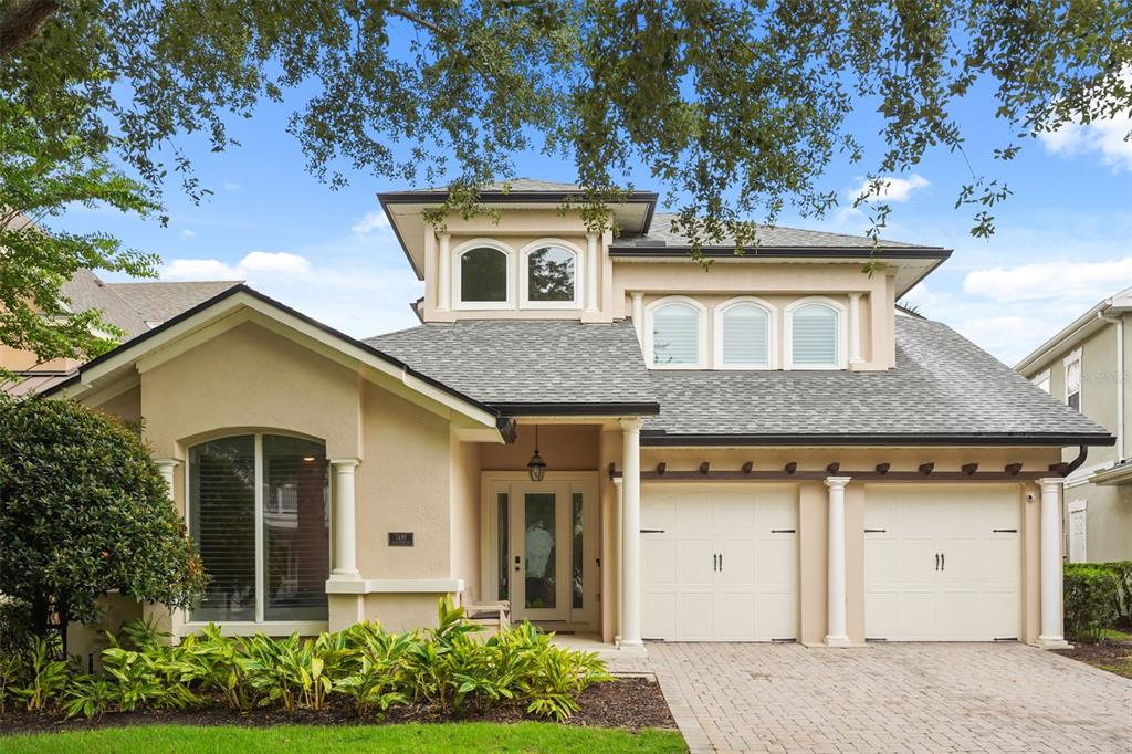 A two-story suburban house with a beige stucco exterior, a two-car garage, and arched windows — 7491 GATHERING DRIVE, KISSIMMEE, FL