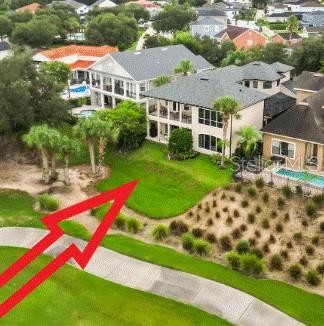 An aerial view shows a multi-story house with a backyard lawn near a golf course — 7491 GATHERING DRIVE, KISSIMMEE, FL