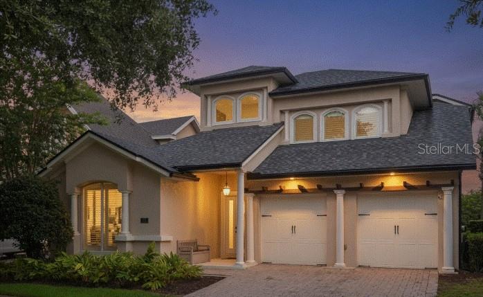 A two-story house with a beige stucco exterior, a two-car garage, and a paved driveway — 7491 GATHERING DRIVE, KISSIMMEE, FL