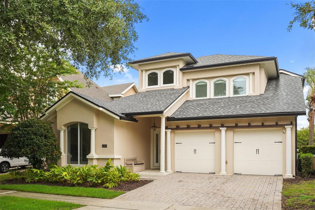 A two-story house with a beige stucco exterior, a shingled roof, and a two-car garage — 7491 GATHERING DRIVE, KISSIMMEE, FL