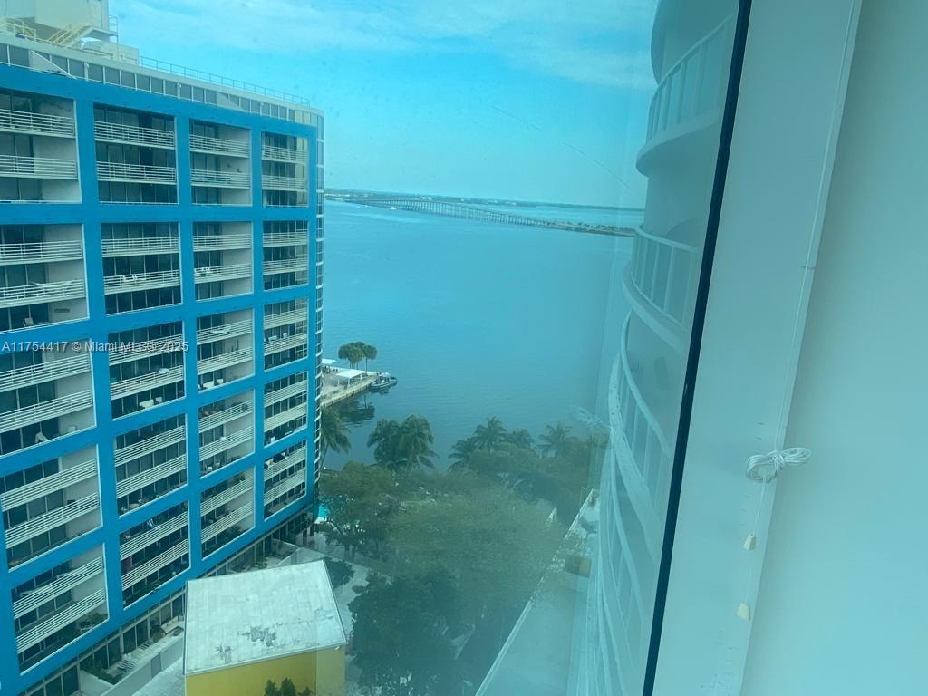 A high-angle view from a window shows a blue building, water, and a bridge — 2101 Brickell Ave # 1401, Miami FL 33129, MIAMI, FL