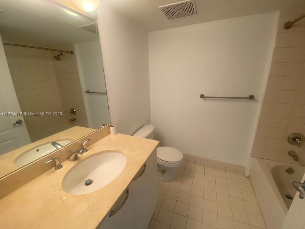 A bathroom features a vanity with a light-colored countertop, a toilet, and a bathtub — 2101 Brickell Ave # 1401, Miami FL 33129, MIAMI, FL