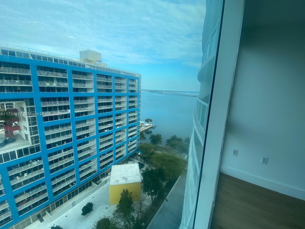 A view from a high-rise window overlooking a blue apartment building and a bay — 2101 Brickell Ave # 1401, Miami FL 33129, MIAMI, FL