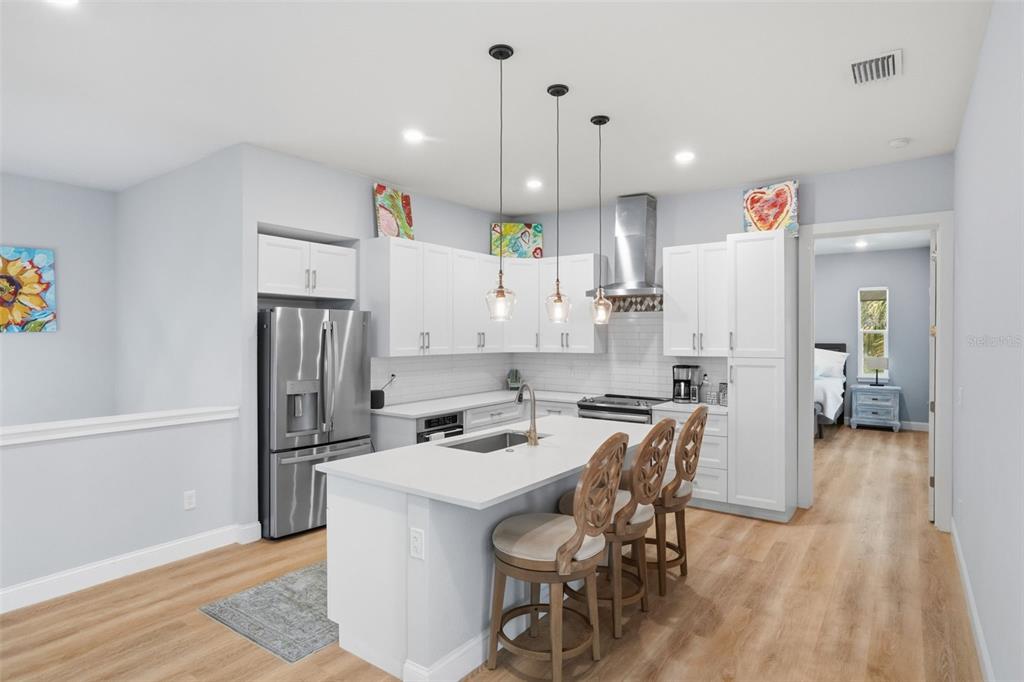 A modern kitchen features white cabinetry, a central island with bar seating, and stainless appliances — 4817 LIMESTONE DRIVE, PORT RICHEY, FL