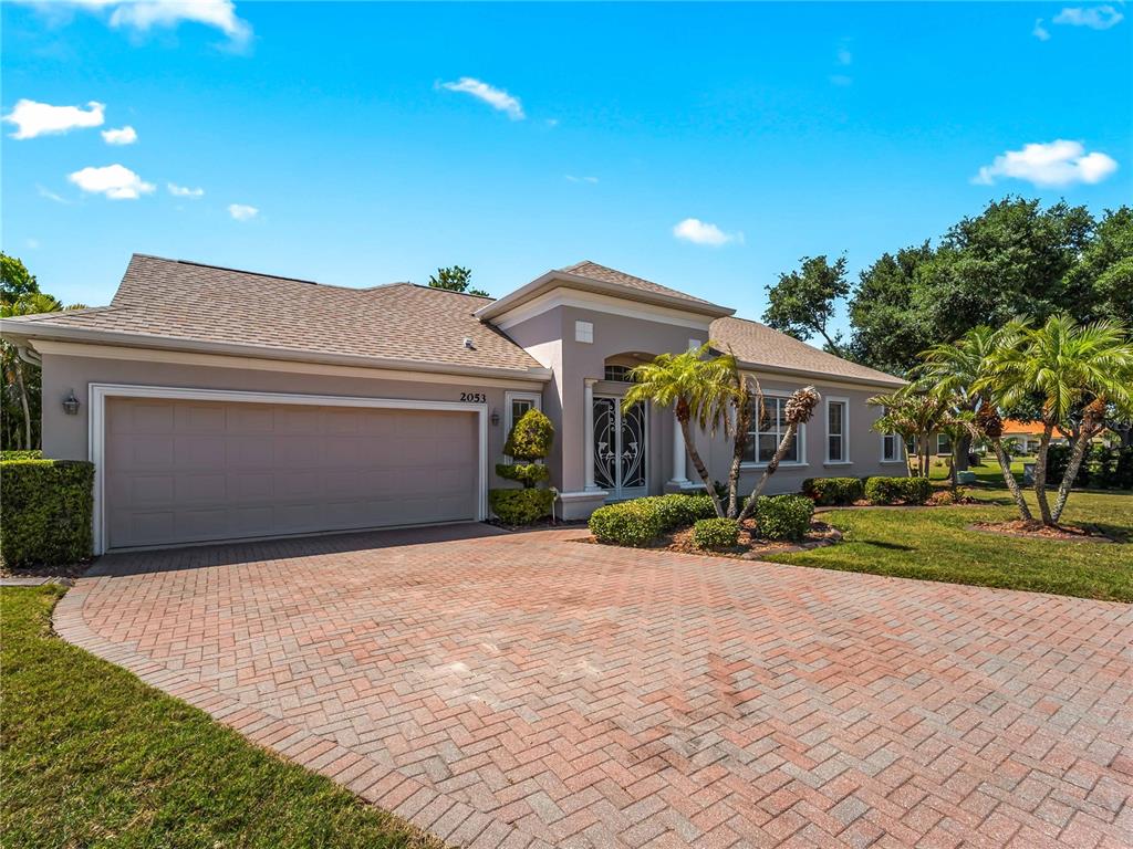 A single-story house with a brick paver driveway, a two-car garage, and palm trees — 2053 MATTAMY CT, VENICE, FL