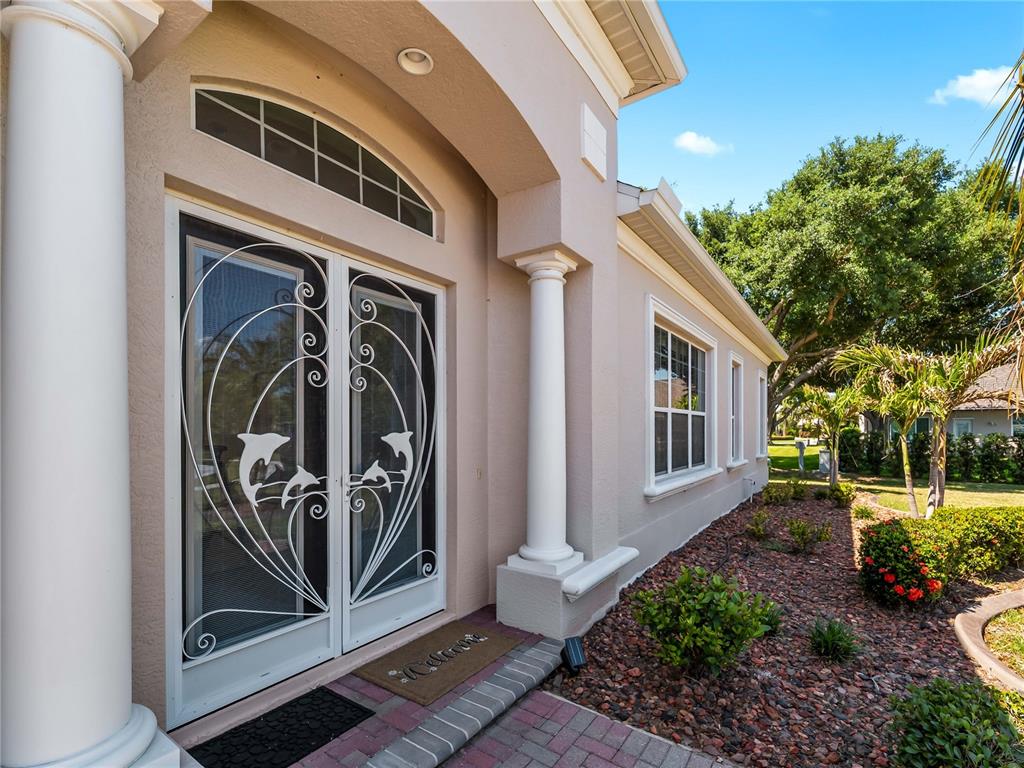 The exterior entrance features double glass doors with white dolphin-themed metal security grilles — 2053 MATTAMY CT, VENICE, FL