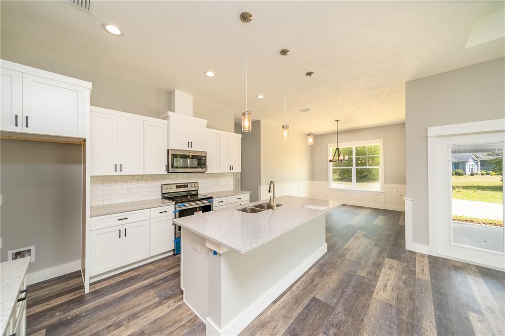 A modern kitchen features white cabinets, a granite island, and wood-look flooring in an open space — 0 71ST LANE, O'BRIEN, FL