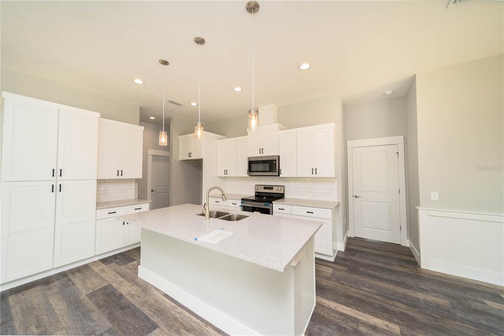 A kitchen features white cabinetry, a central island with a sink, and dark wood flooring — 0 71ST LANE, O'BRIEN, FL