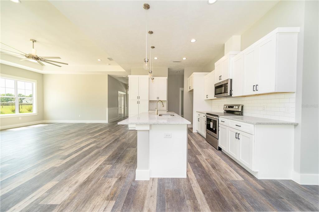 A modern kitchen features white cabinets, a granite-topped island, and wood-look flooring — 0 71ST LANE, O'BRIEN, FL