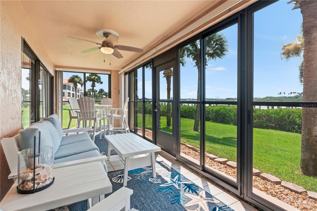 A sunroom with a ceiling fan, light blue sofa, and sliding glass doors overlooking a lawn — 460 BOUCHELLE DRIVE UNIT 101, NEW SMYRNA BEACH, FL