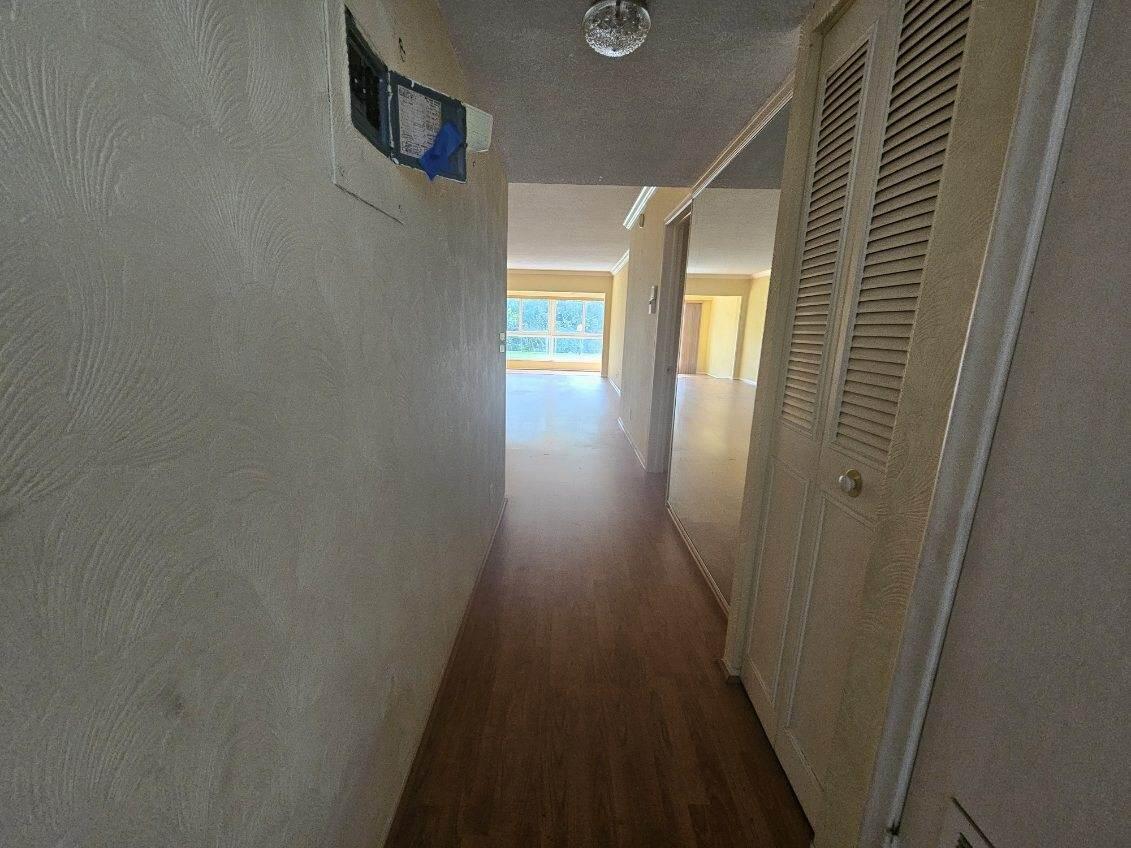 A hallway with wood-look flooring leads toward a bright room with large windows — 3401 Spanish Trail # 152, Delray Beach FL 33483, DELRAY BEACH, FL