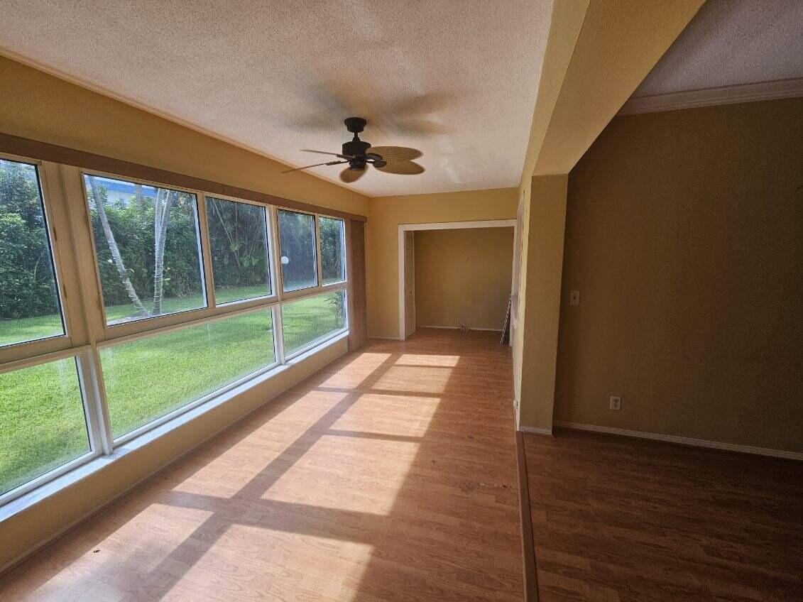 A sunroom with light wood-look flooring, large windows, and a ceiling fan — 3401 Spanish Trail # 152, Delray Beach FL 33483, DELRAY BEACH, FL