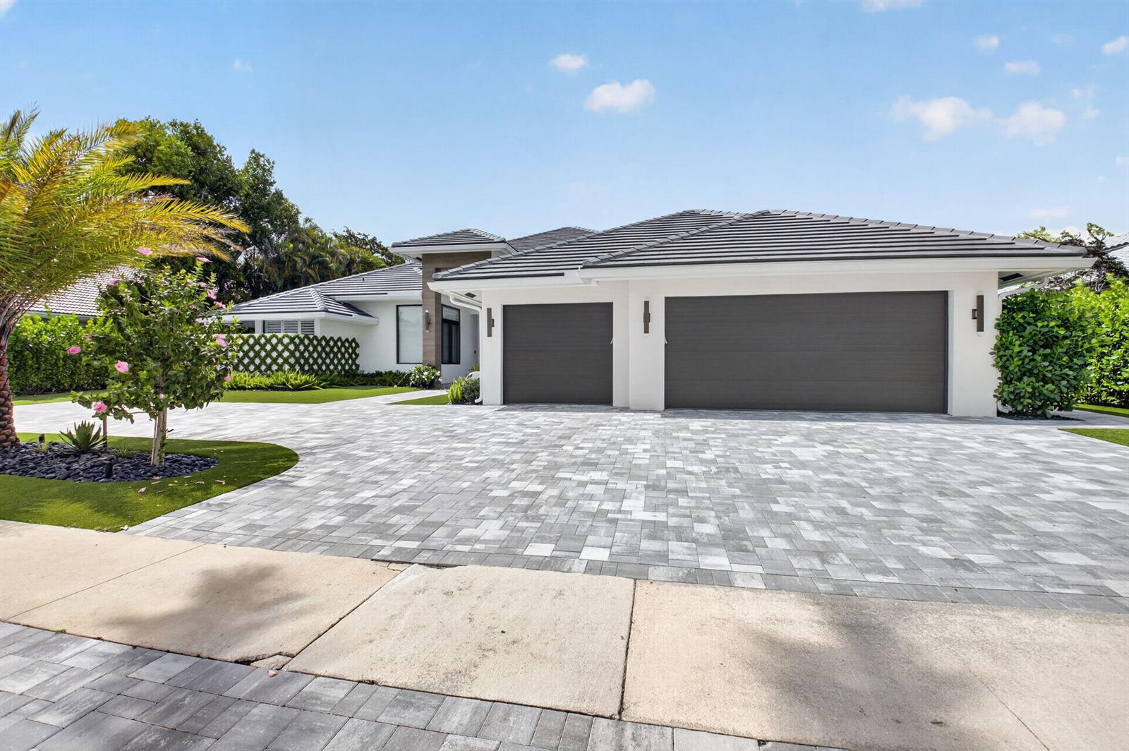 A modern single-story house features a large paver driveway, a three-car garage, and landscaping — 3954 NW 52nd Street, Boca Raton FL 33496, BOCA RATON, FL