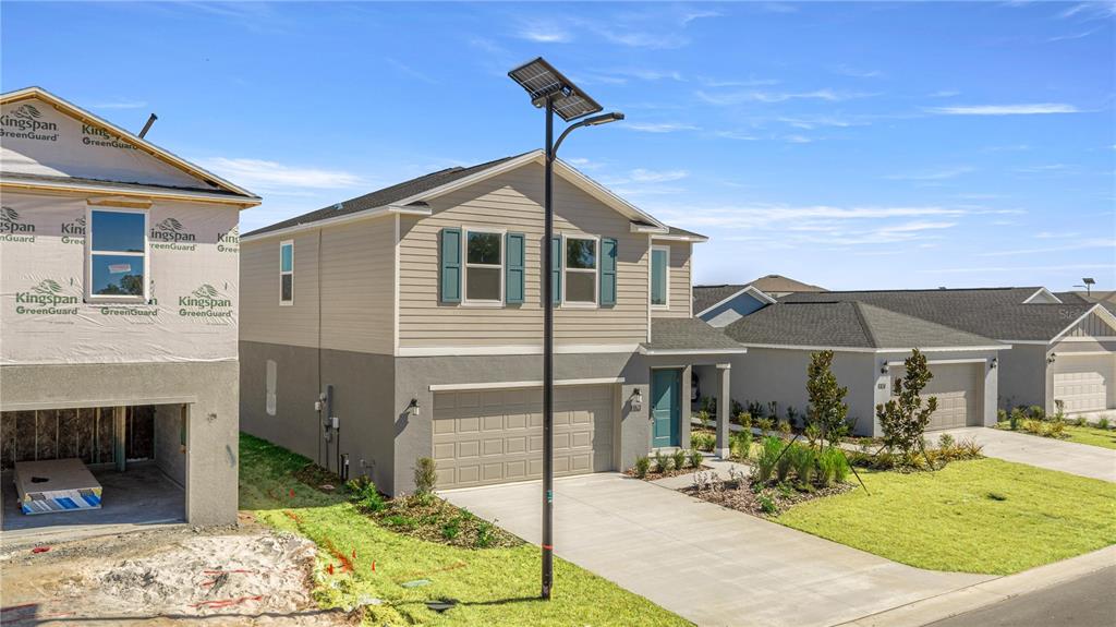 A two-story house with a tan exterior and a solar-powered streetlamp in the front yard — 3767 NE 32ND COURT, OCALA, FL