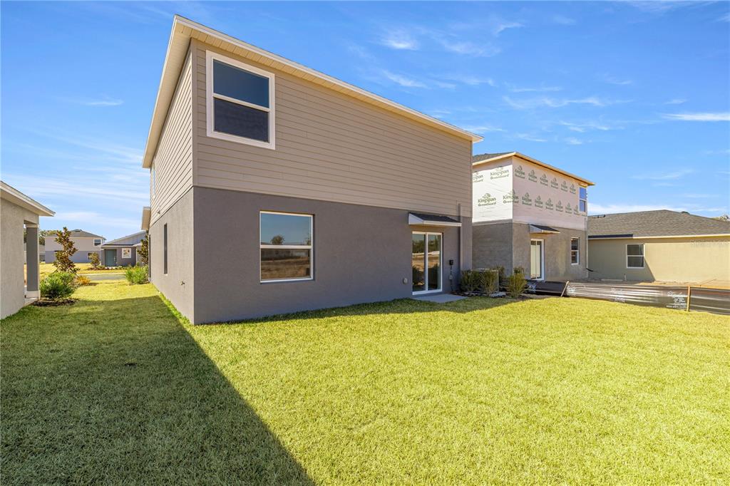 The rear exterior of a two-story house with a gray stucco base and tan siding — 3767 NE 32ND COURT, OCALA, FL