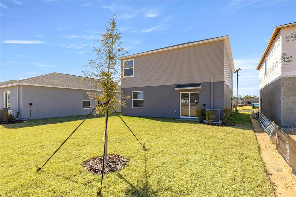 The exterior rear view of a two-story house features a grassy yard and sliding doors — 3767 NE 32ND COURT, OCALA, FL