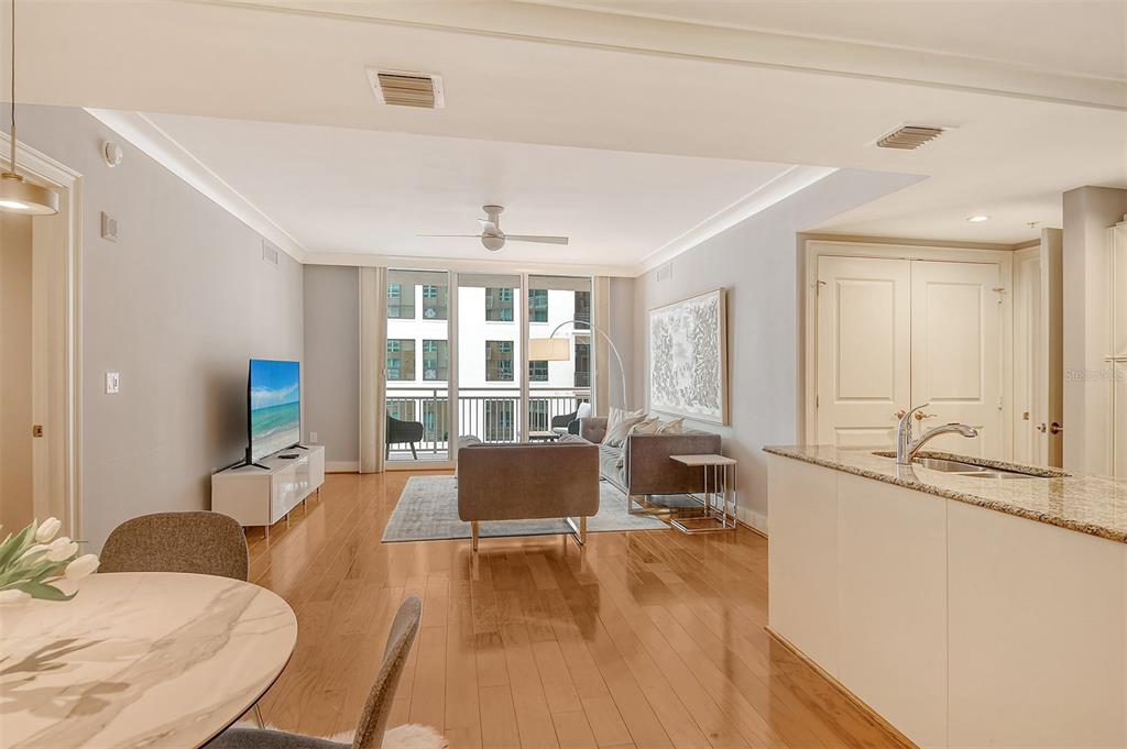 A bright living room features hardwood floors, a balcony, and an open-concept kitchen island — 1350 MAIN STREET UNIT 903, SARASOTA, FL