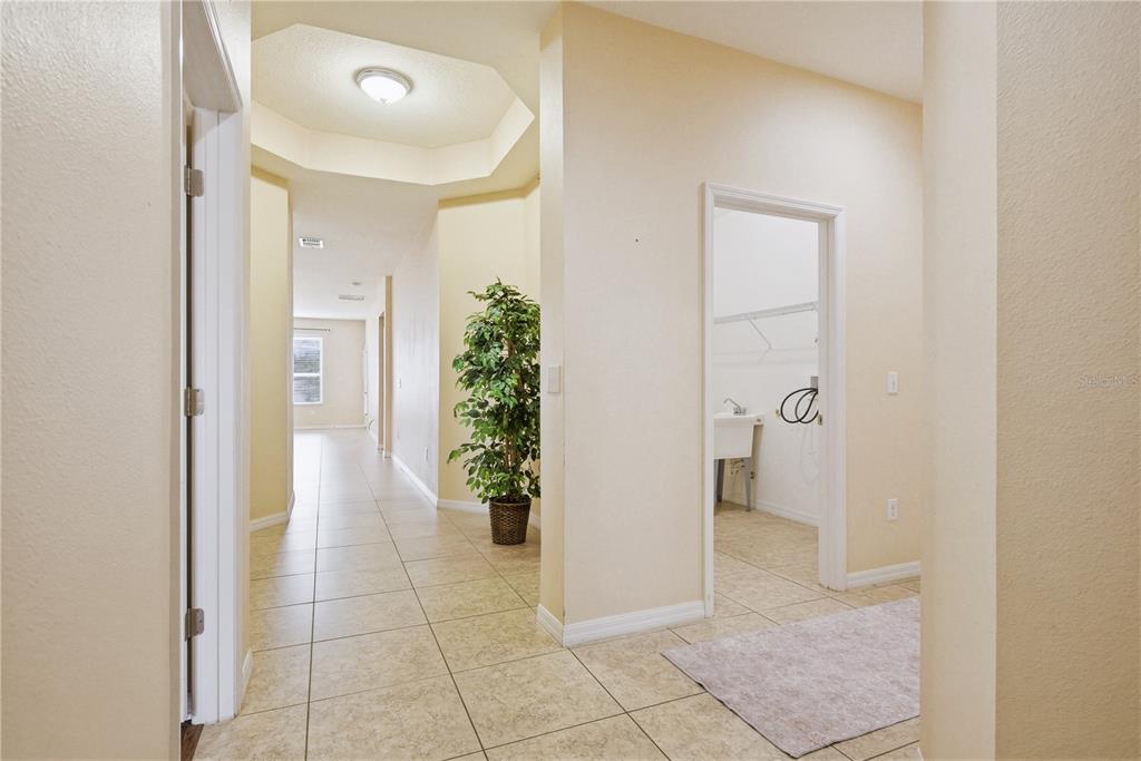 A hallway with tile flooring leads to a laundry room with a utility sink — 2211 BARRACUDA COURT, HOLIDAY, FL