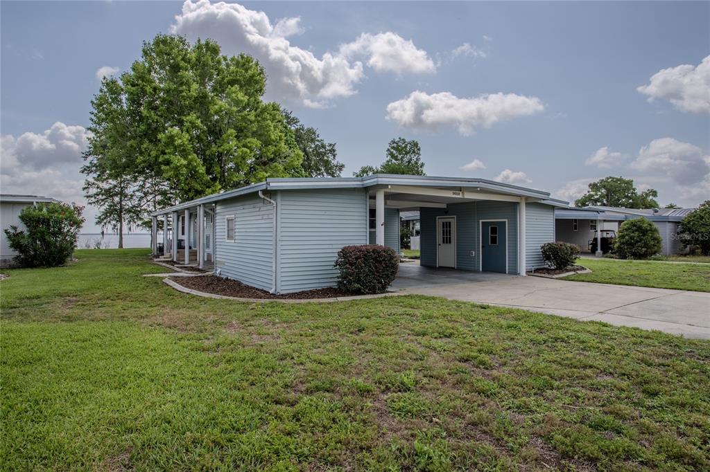 A light blue mobile home with a carport and a view of a lake — 34232 ISLAND DRIVE, LEESBURG, FL