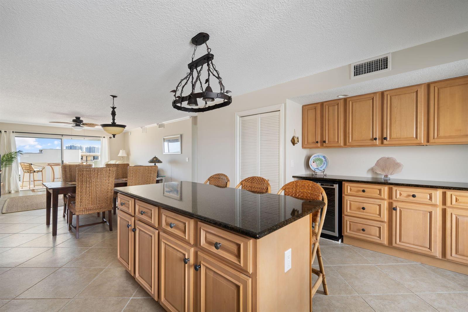 A kitchen with light wood cabinets, a dark granite island, and an adjacent dining area — 4049 Ocean Drive # 505, Vero Beach FL 32963, VERO BEACH, FL