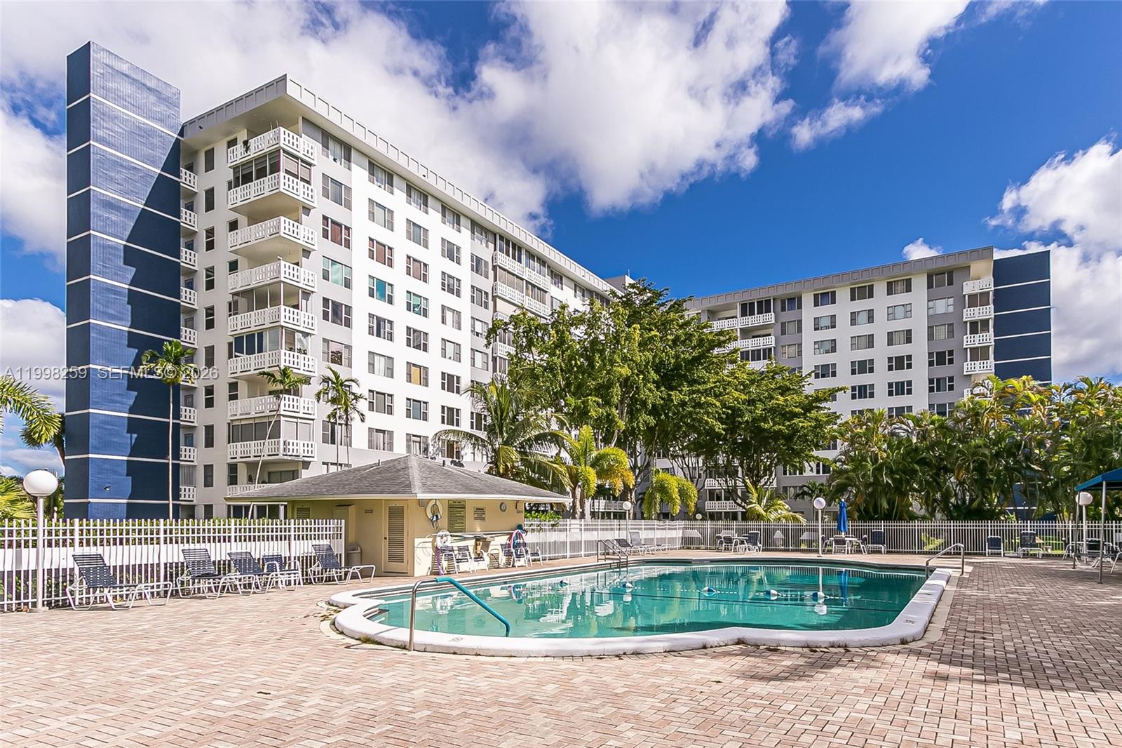 A swimming pool sits on a brick patio in front of a multi-story apartment building — 4350 Hillcrest Dr # 303, Hollywood FL 33021, HOLLYWOOD, FL